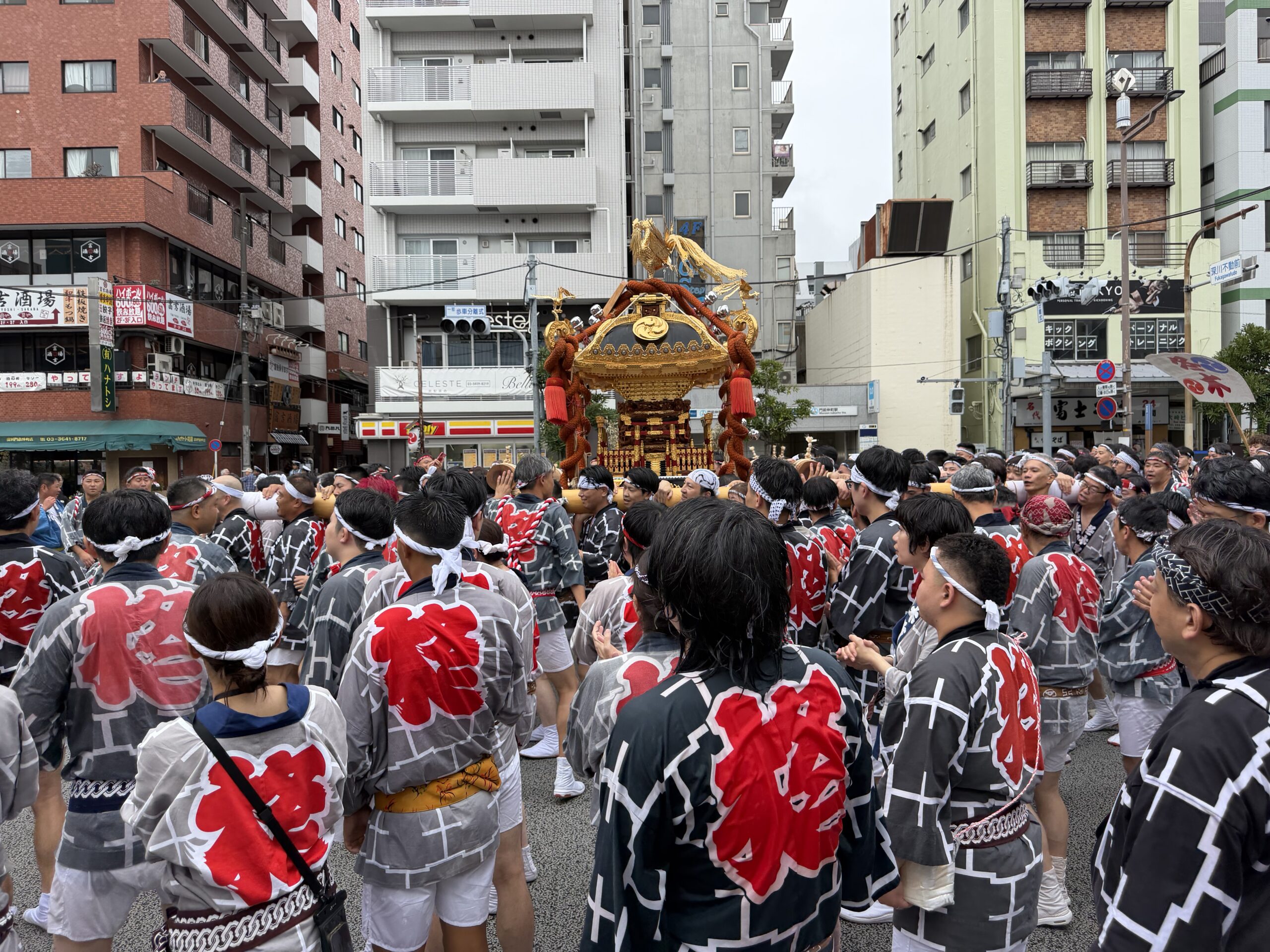 深川の街で大勢の担ぎ手に担がれる金色の神輿
