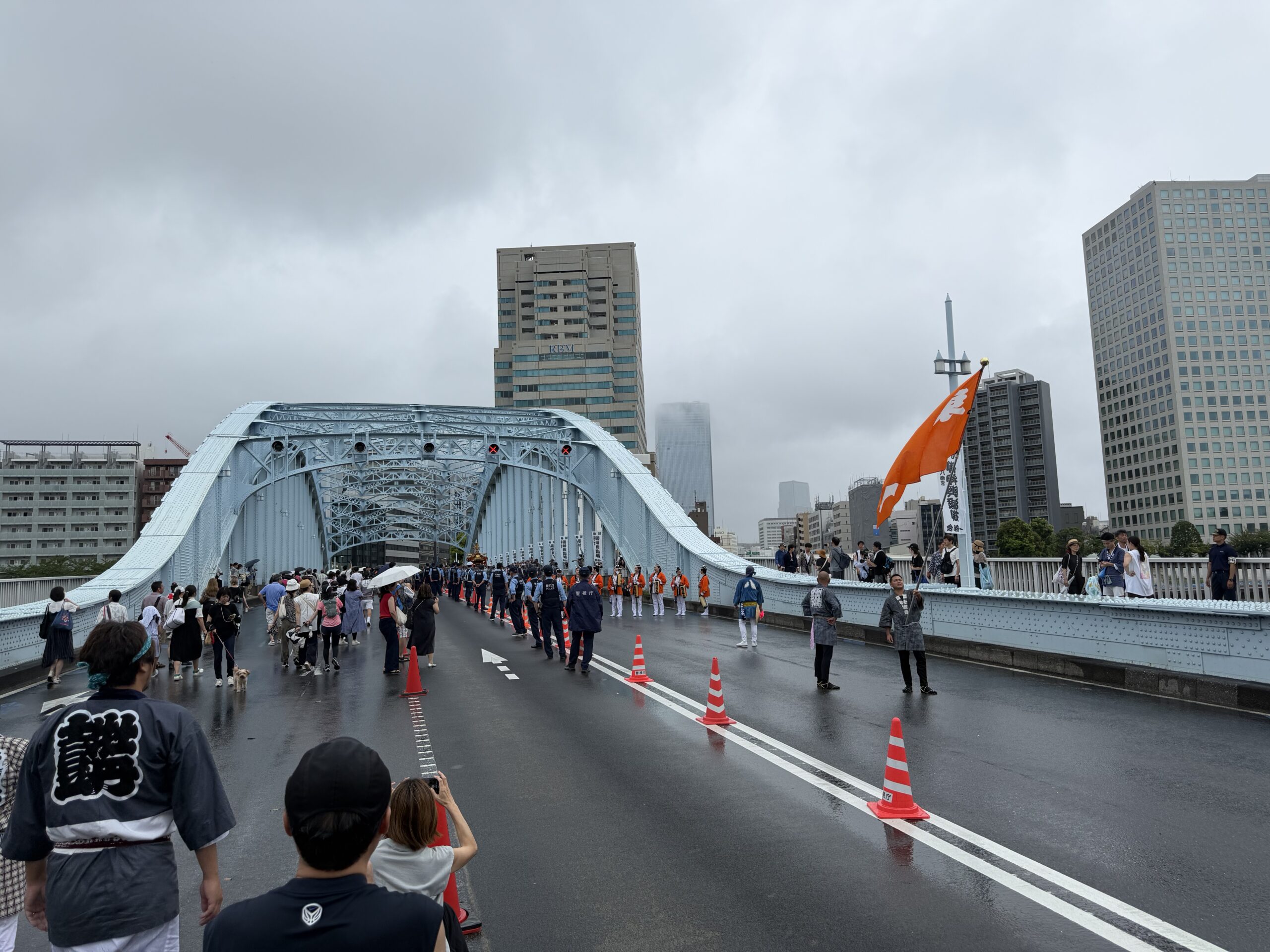 雨で濡れた永代橋を進む深川八幡祭りの一行と見物客